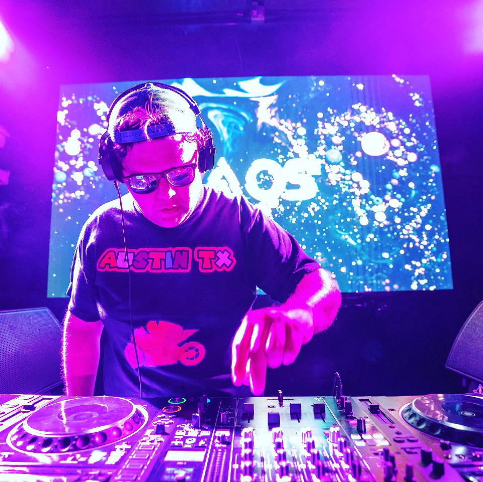 Jose Ortega performing as JAOS at the mixing decks under purple stage lights.